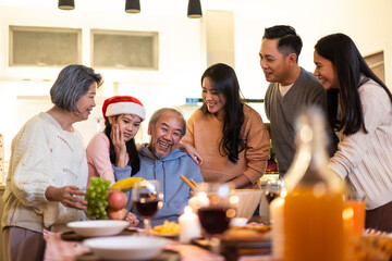 Asian big family preparing foods and drinks to serve on dining table.