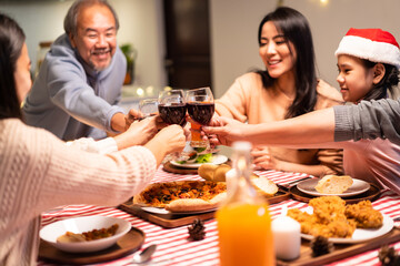 Asian big family clinking wine glasses and enjoying Christmas party.