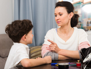 Portrait of strict young woman scolding her teen son in cosy home interior..