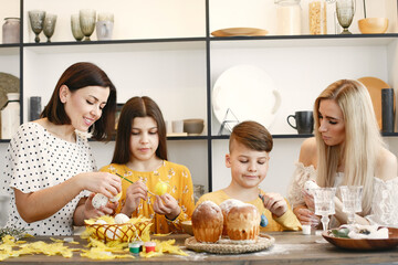 Mother help her children to paint eggs