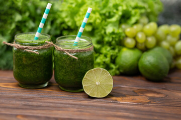 Glasses with green organic smoothie and straw. Green vegetable juice on rustic wooden table....