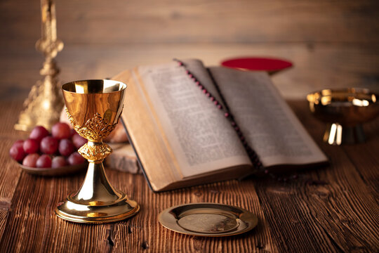 Catholic religion concept. Catholic symbols composition. The Cross, Holy Bible and golden chalice on the altar.