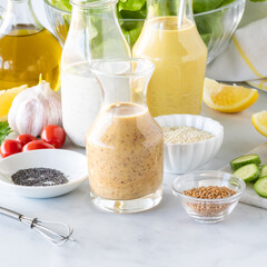 Close up of homemade salad dressings including honey mustard, poppyseed and turmeric tahini.