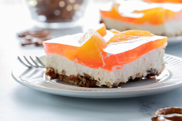 Close up of a slice of peach jelly pretzel dessert brightly lit from behind, ready for eating.