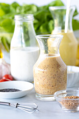Close up of three homemade salad dressings in bottles with honey mustard dressing in front. 
