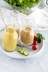 Three homemade salad dressing including turmeric tahini, honey mustard and poppyseed, taken from above.