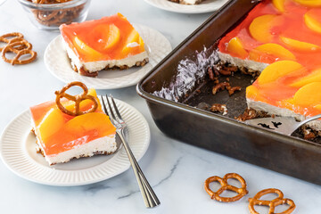 Close up of a slice of peach jelly pretzel dessert garnished with a pretzel, ready for eating.
