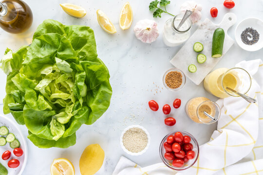 Top down view of a head of butter lettuce leaves surrounded by homemade salad dressing and other ingredients.