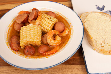 Homemade Cajun Shrimp Boil with Corn, New Potatoes, and Andouille Sausage with a Slice of Sourdough Bread