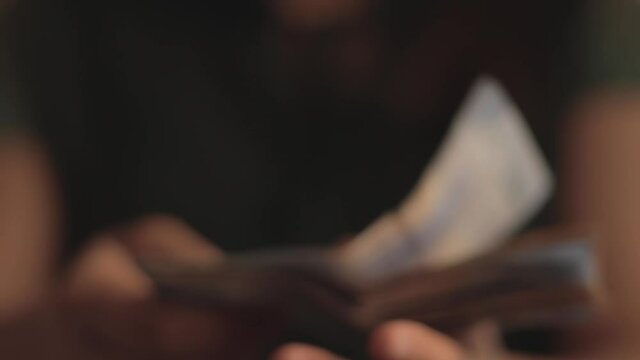 Close up of woman's hands with short nails, showing Mexican five hundred peso bills.