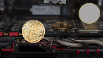 Gold coin with bitcoin symbol on motherboard, concept of mining video card