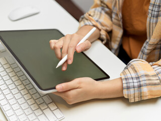 Side view of female freelancer working with digital tablet on computer table
