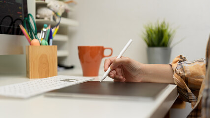 Female graphic designer working with digital tablet on computer table with stationery and supplies