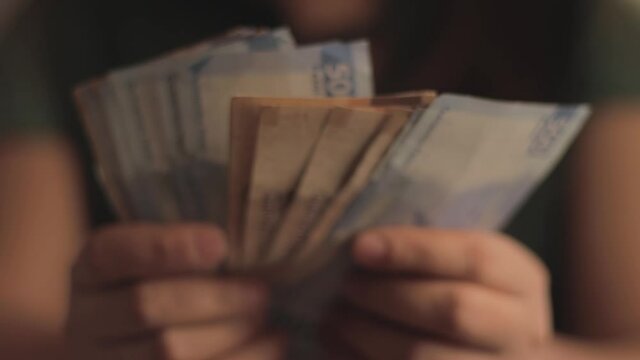 Woman showing five hundred Mexican pesos bills.