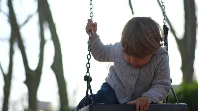 Little baby trying to climb playground swing