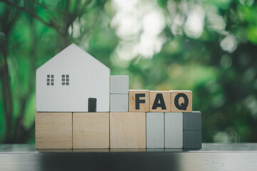 Wooden blocks with the word FAQ place with white home. The concept of FAQ about house problems.