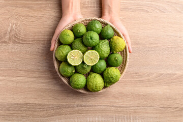 Fresh bergamot fruit in a basket holding by woman hand on wooden background, Food ingredients and extract used for medicine, tea, perfumes and cosmetics