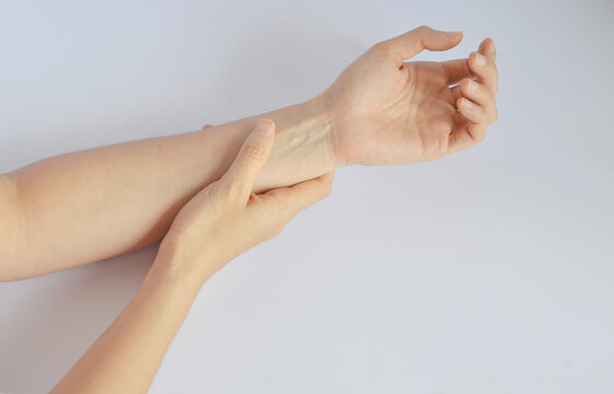 Hand massaging arm wrist with visible blood vessel in white background
