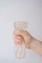 Boy hand holding an artificial realistic vagina, male sex on bed sheet, natural lighting for cozy feeling at home.