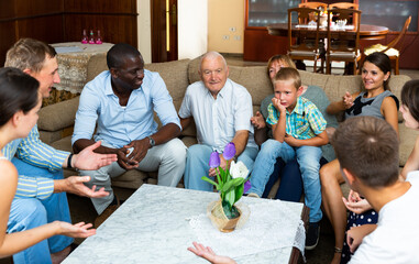 Obraz premium Big international family gathered together in parental home, cheerfully talking in living room