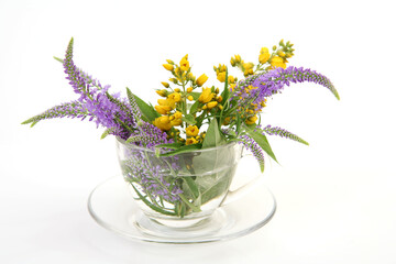 bouquet of wildflowers in a transparent mug on a white background
