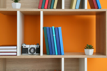 Obraz na płótnie Canvas Shelf unit with books and decor on color background