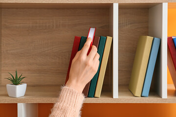 Woman taking book from shelf, closeup