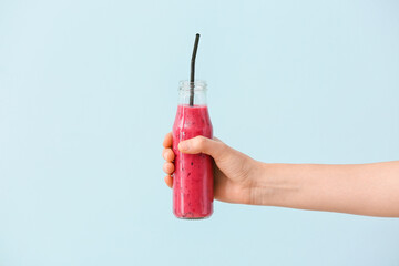 Woman with bottle of fruit smoothie on color background