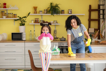 Mother and daughter cleaning table in kitchen