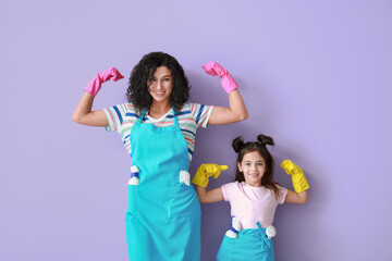 Mother and daughter with cleaning supplies on color background