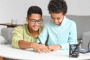 African-American boy helping his little brother to do lessons at home