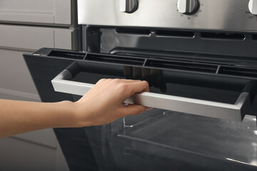 Woman opening oven in kitchen