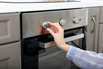 Woman adjusting oven in kitchen