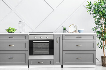 Fototapeta premium Modern furniture with oven near light wall in kitchen