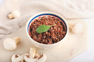 Bowl with tasty quinoa and mushrooms on light background