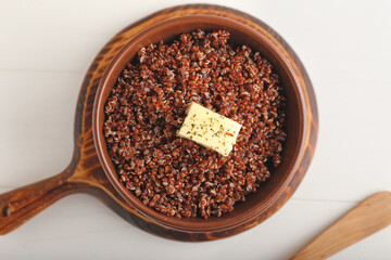 Bowl with tasty quinoa and butter on light background