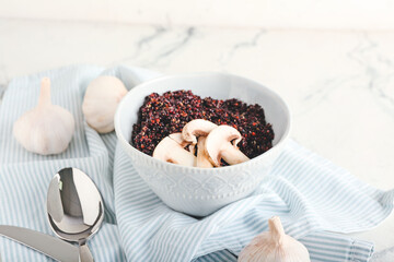 Bowl with tasty quinoa, mushrooms and garlic on light background