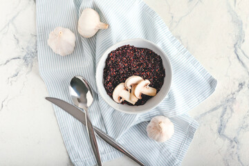 Bowl with tasty quinoa, mushrooms and garlic on light background