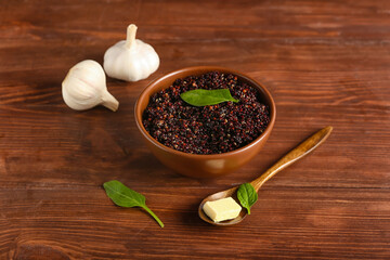 Composition with tasty quinoa, butter and garlic on wooden background