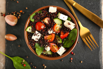 Bowl with tasty quinoa salad on dark background