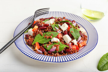Plate with tasty quinoa salad on white wooden background