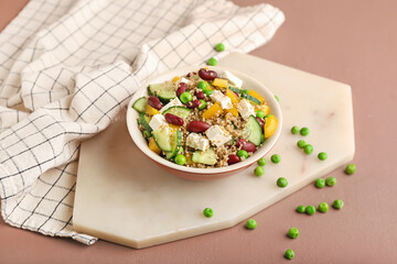 Bowl with tasty quinoa salad on color background
