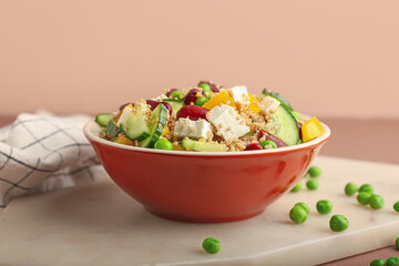 Bowl with tasty quinoa salad on color background