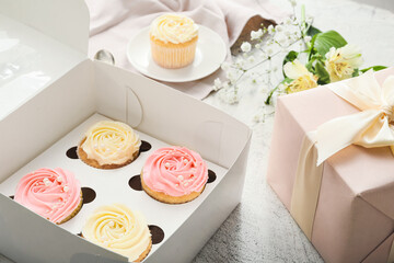 Composition with tasty cupcakes and flowers on light background, closeup
