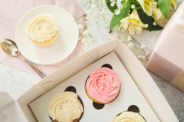 Composition with tasty cupcakes and flowers on light background, closeup