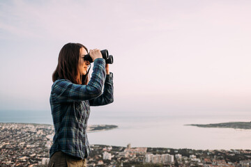 Woman explorer looks through binoculars in the mountains. - 431843287
