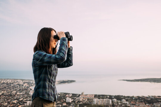 Woman explorer looks through binoculars in the mountains.