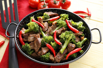 Tasty beef with vegetables on color wooden background