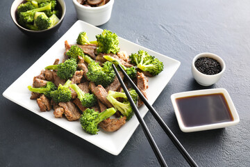 Plate with tasty beef and broccoli on dark background