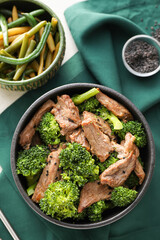 Bowl with tasty beef and broccoli on table